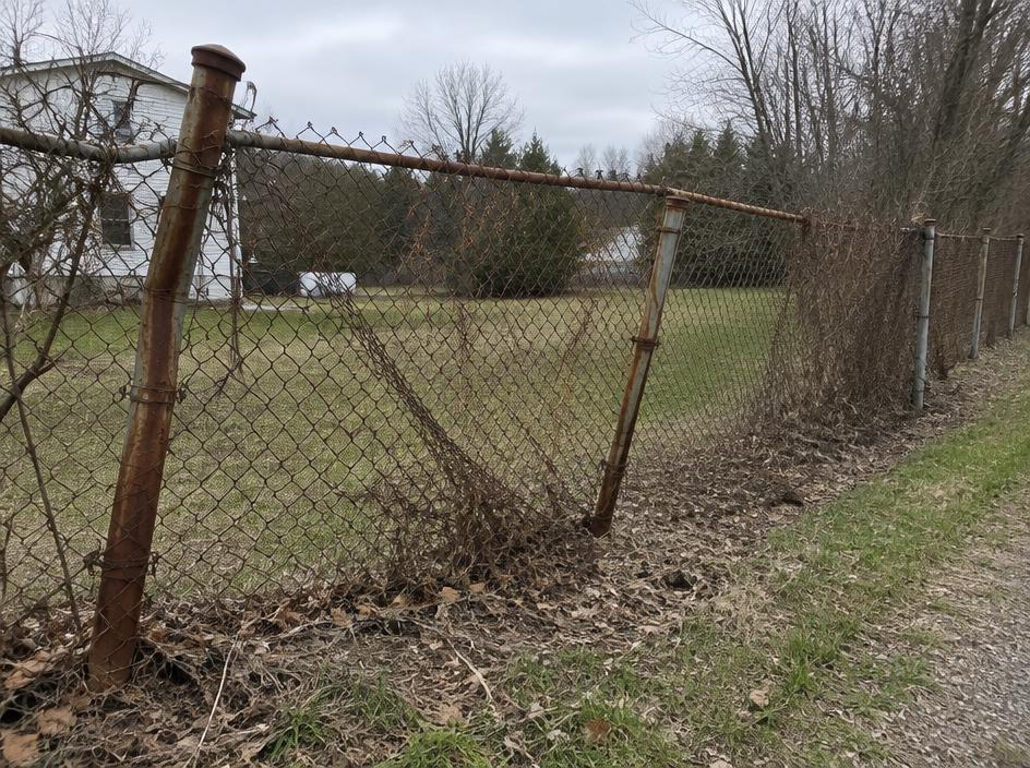 Rusted, damaged chain link fence with bent posts